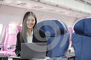 Female passenger sitting on plane while working on laptop computer with simulated space using on board wireless