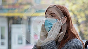 Female passenger wearing gloves puts medical mask on her face while traveling in public transport, precautionary