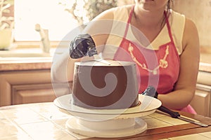 A female pastry chef flattens the chocolate cake with a spatula