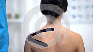 Female patient with applied Y-shaped tape on shoulder, alternative medicine