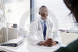 Female Patient In Consultation With Doctor Sitting At Desk In Office