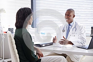 Female Patient In Consultation With Doctor Sitting At Desk In Office