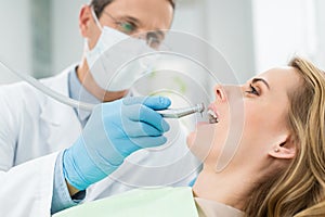 Female patient at dental procedure using dental drill in modern