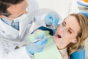 Female patient at dental procedure using dental drill in modern