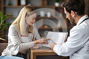 Female Patient Discussing Blood Test Results With Doctor During Meeting In Office