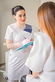 Female Patient And Doctor Have Consultation In medical clinic, writing notes