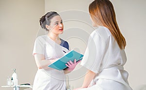 Female Patient And Doctor Have Consultation In medical clinic, writing notes