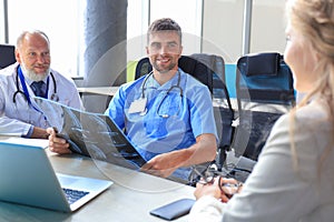 Female patient and doctors have consultation in hospital room