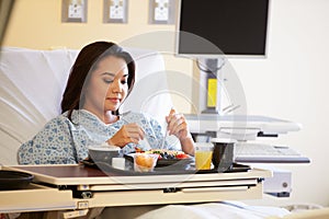 Female Patient Enjoying Meal In Hospital Bed