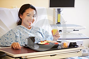 Female Patient Enjoying Meal In Hospital Bed