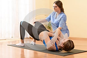 Female patient exercising with her physiotherapist using resistance band. Physical therapy concept.