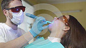 Female patient getting treatment with dental UV light equipment. Dental office.