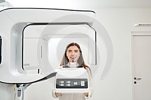 Female patient having her teeth scanned with tomograph