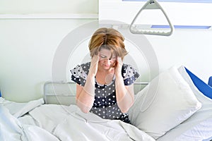 Female patient with headache on bed in hospital ward