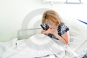 Female patient With heartfelt pain lying on bed in hospital ward