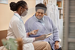 Female Patient Listening to Doctor Holding Tablet