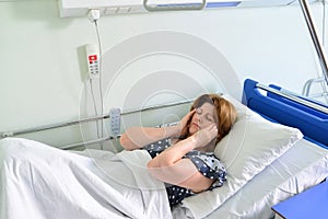Female patient lying on bed in hospital ward