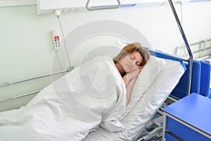 Female patient lying on bed in hospital ward