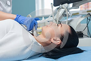 Female patient is lying on a couch during the procedure of ultrasound diagnosis of the thyroid gland. Prevention of