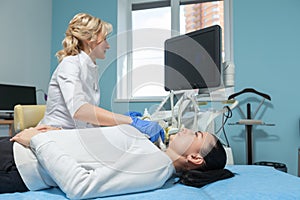 Female patient is lying on a couch during the procedure of ultrasound diagnosis of the thyroid gland. Prevention of