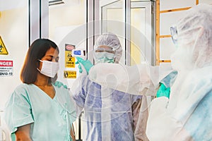 The female patient measured body temperature with a temperature gun by the medical team in front of the containment room.