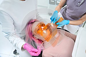 Female patient in protective glasses lies in a dental chair