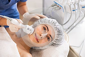 Female patient receiving hardware facial procedure using cooling attachment