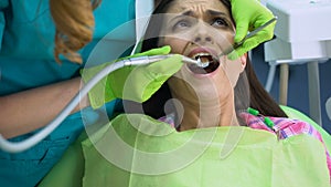 Female patient scared of dental drill, painful procedure, sensitive teeth