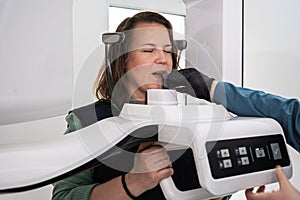 A female patient stands still in dental X-ray machine to create a detailed image teeth