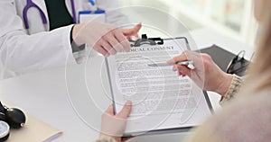 Female patient studying reads signing informed consent in doctor office