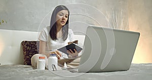 Female patient talking to online doctor showing pills and capsules using laptop at home. Telemedicine