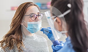 Female patient wearing mask over mouth is having sample taken from nose for a pcr test for Covid 19