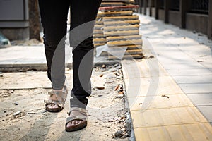 Female pedestrians people is walking on a footpath walkway under construction and stacked cobblestone block or renovation,damaged photo