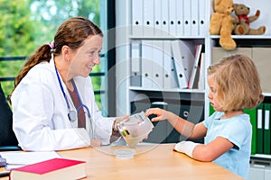 Female pediatrician has candys for a little girl