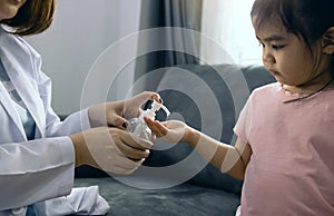 Female pediatrician is holding a bottle of alcohol hand sanitizer gel to wash hands kill germs and bacteria for children during