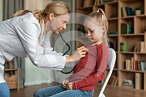 Female pediatrician with stethoscope listening to heartbeat girl's patient on medical exam during home visit