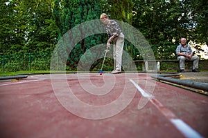 Female pensioner at the end of the minigolf court is preparing f