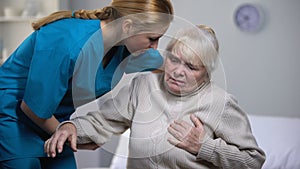 Female pensioner feeling sudden heart pain, nurse helping old patient, health