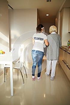 Female pensioner and her caregiver leaving the kitchen