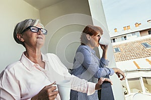 Female pensioners relaxing with cup of coffee on balcony
