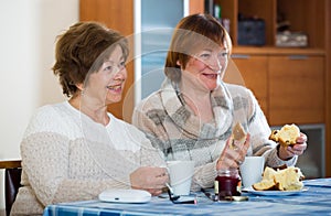 Female pensioners watching TV channel and drinking tea