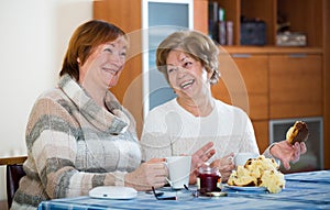 Female pensioners watching TV channel and drinking tea