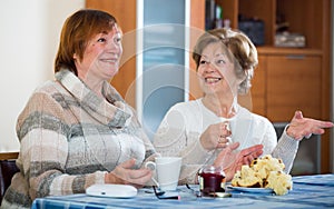 Female pensioners watching TV channel and drinking tea