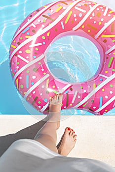 Female with perfect red pedicure over a pool. Vacation pericure. Female with bare feet over blue swimming pool water