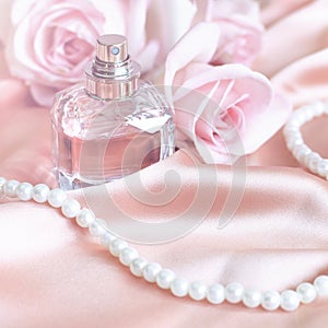 Female perfume bottle, rose, pearls on pink silk