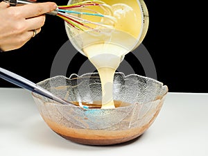 Female person pouring Gogl-Mogl, into a glass bowl