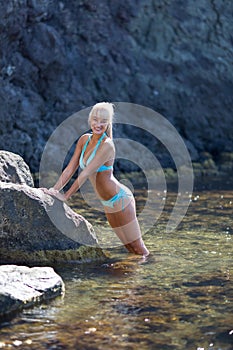 Female person resting at secluded place of wild rocky seashore