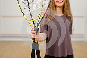 Female person shows squash racket and ball