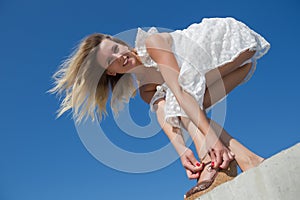 Female person in white dress bends