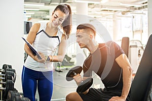 Female personal trainer showing exercise results to her male client in a gym